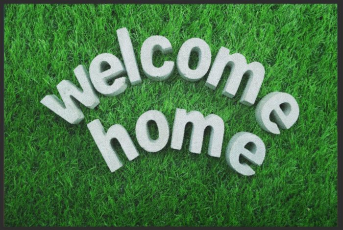 Fußmatte „welcome home“ auf grünem Rasen